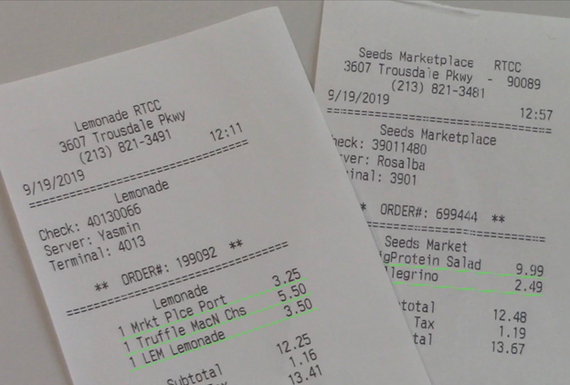 Two paper receipts photographed at a tilted angle showing printed text