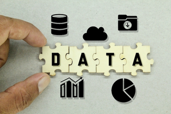 Hands assembling puzzle pieces spelling DATA surrounded by database and chart icons