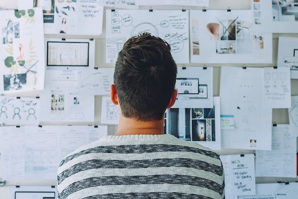 Person reviewing a wall covered with planning documents, diagrams, and strategy notes